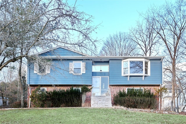 raised ranch with a front yard and brick siding