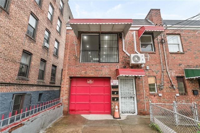 multi unit property featuring ac unit, fence, concrete driveway, a garage, and brick siding