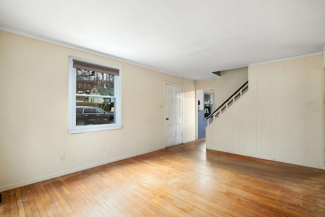 unfurnished living room with stairway, baseboards, and light wood-style floors