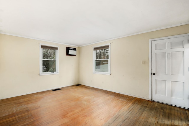 unfurnished room with hardwood / wood-style floors, visible vents, and ornamental molding