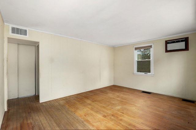 spare room with crown molding, visible vents, and light wood finished floors