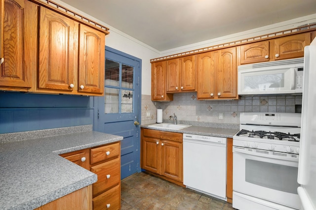 kitchen with decorative backsplash, white appliances, brown cabinetry, and a sink