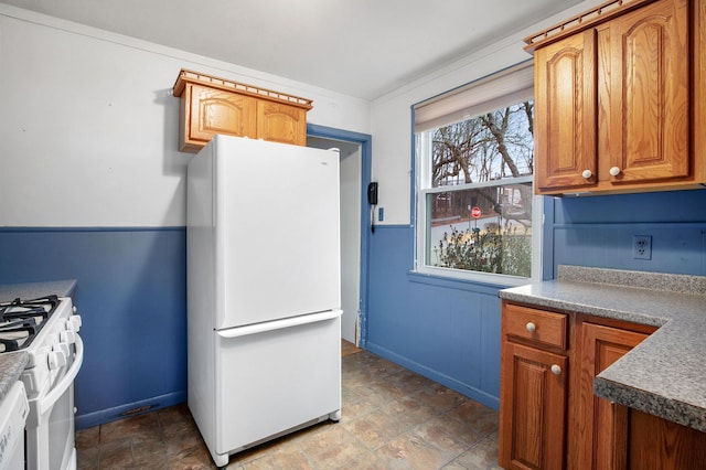 kitchen featuring brown cabinetry, stone finish floor, and white appliances