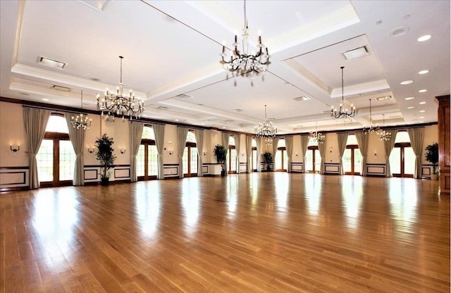 miscellaneous room featuring a raised ceiling, a notable chandelier, wood finished floors, and ornamental molding