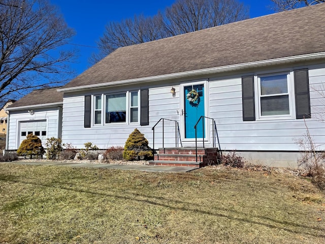 view of front of property with a front yard, an attached garage, and a shingled roof