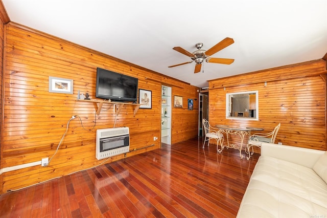 living area with heating unit, ceiling fan, and wood finished floors