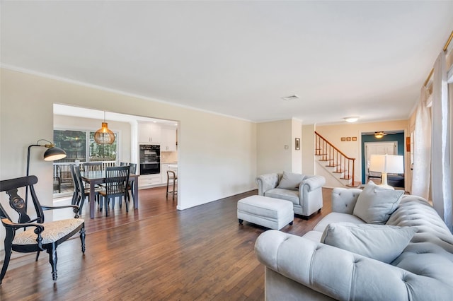 living area with stairway, dark wood-type flooring, visible vents, and ornamental molding