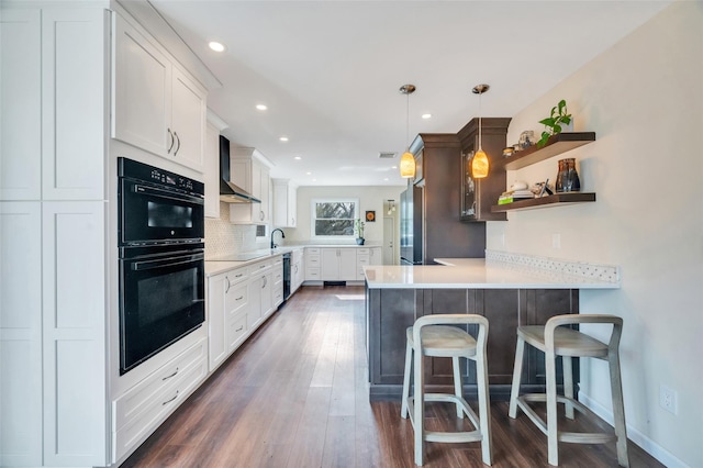 kitchen featuring black appliances, a peninsula, wall chimney exhaust hood, and light countertops