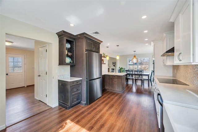 kitchen with range hood, visible vents, freestanding refrigerator, light countertops, and black electric cooktop