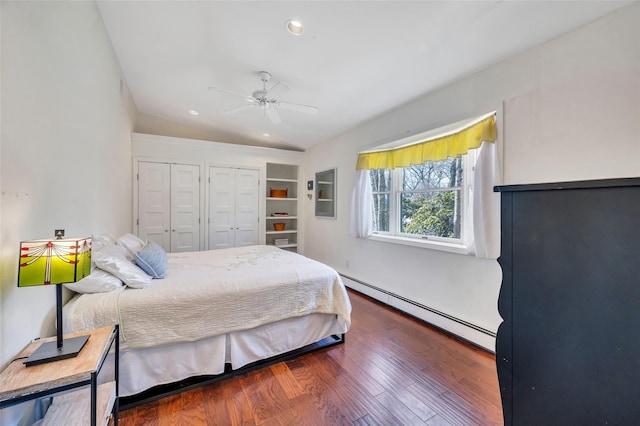 bedroom featuring multiple closets, wood finished floors, recessed lighting, baseboard heating, and vaulted ceiling