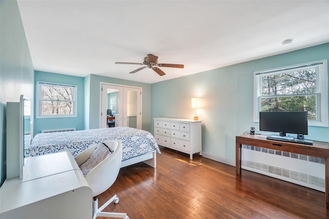 bedroom with baseboards, multiple windows, radiator, and wood finished floors