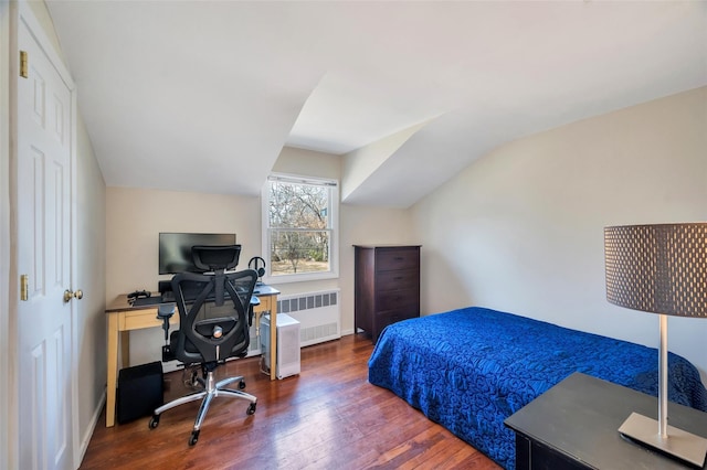 bedroom with vaulted ceiling, radiator heating unit, and wood finished floors