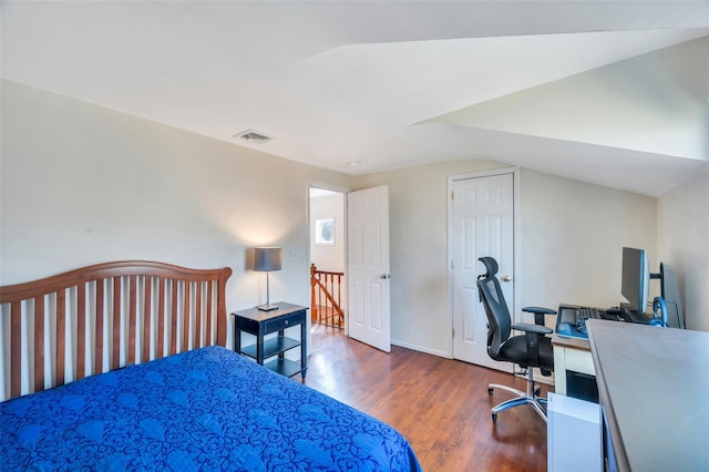 bedroom with visible vents, lofted ceiling, baseboards, and wood finished floors