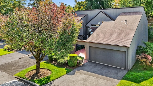 view of front of home featuring an attached garage, driveway, and a shingled roof