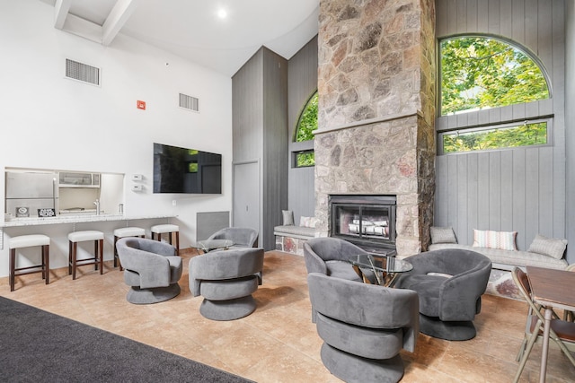 tiled living room with visible vents, a towering ceiling, and a large fireplace