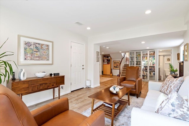 living area featuring light wood-type flooring, visible vents, recessed lighting, baseboards, and stairs