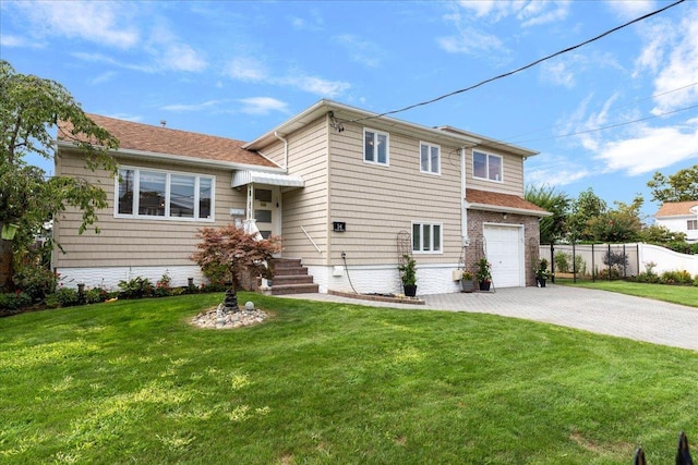 tri-level home featuring decorative driveway, a garage, a front lawn, and fence