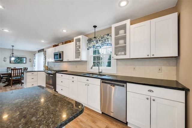 kitchen with a sink, stainless steel appliances, light wood-style floors, and white cabinetry