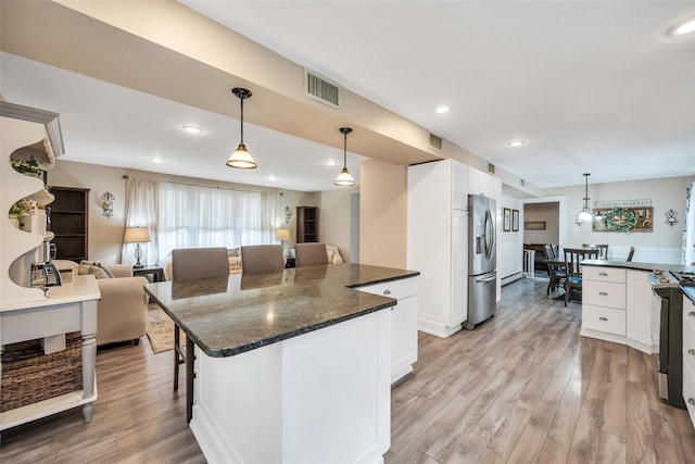 kitchen with visible vents, a breakfast bar, light wood-style floors, and open floor plan