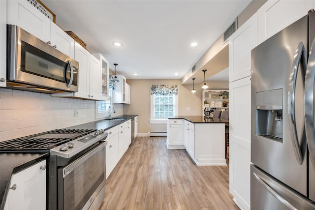 kitchen featuring dark countertops, visible vents, light wood finished floors, stainless steel appliances, and a sink