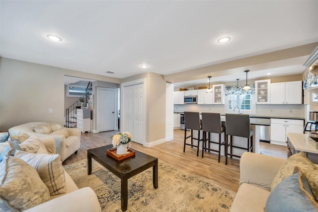 living area with stairway, recessed lighting, light wood-style floors, and baseboards