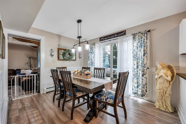 dining area with a baseboard radiator, light wood finished floors, and wainscoting