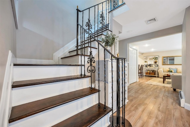 staircase with visible vents, a baseboard radiator, and wood finished floors