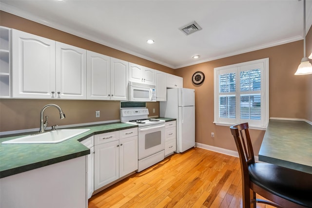 kitchen with visible vents, a sink, dark countertops, white appliances, and white cabinets