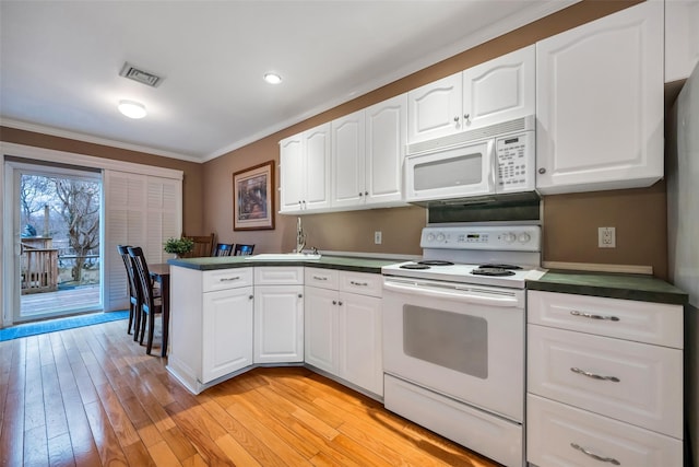 kitchen featuring light wood finished floors, visible vents, dark countertops, ornamental molding, and white appliances