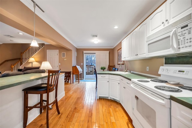 kitchen with light wood finished floors, visible vents, white appliances, white cabinetry, and a sink