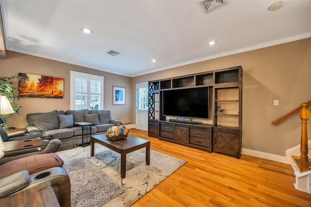 living room with light wood-type flooring, visible vents, baseboards, and ornamental molding