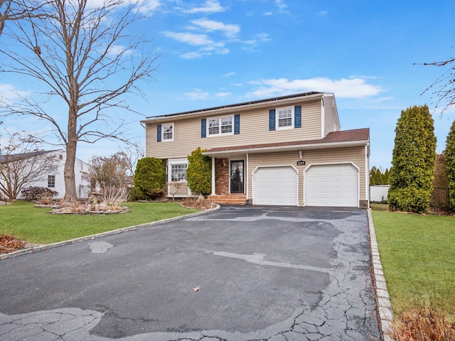 view of front facade with a front yard, an attached garage, roof mounted solar panels, and aphalt driveway