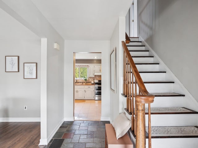 stairway with stone tile floors and baseboards