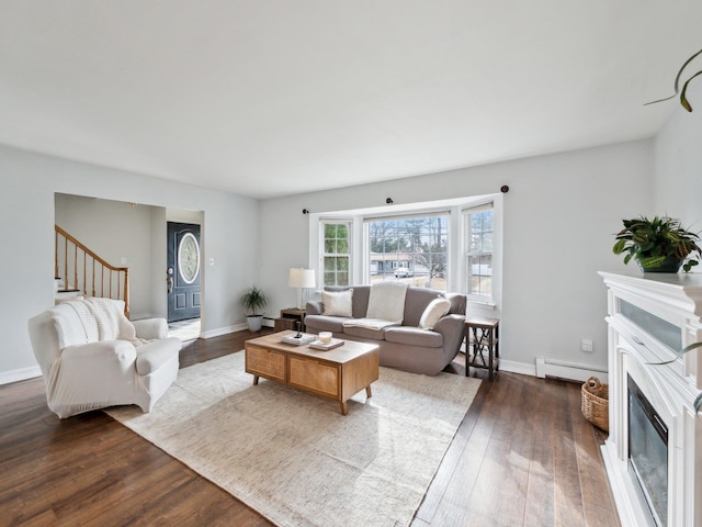 living area with baseboards, stairs, dark wood-style floors, a glass covered fireplace, and a baseboard radiator