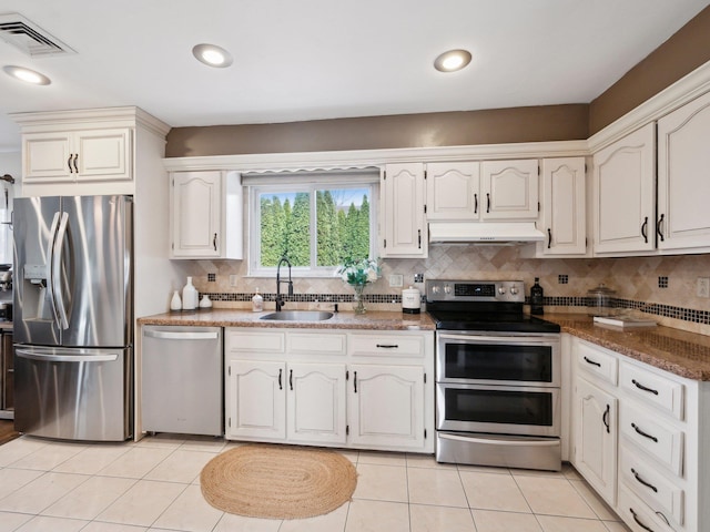 kitchen with visible vents, a sink, under cabinet range hood, backsplash, and appliances with stainless steel finishes