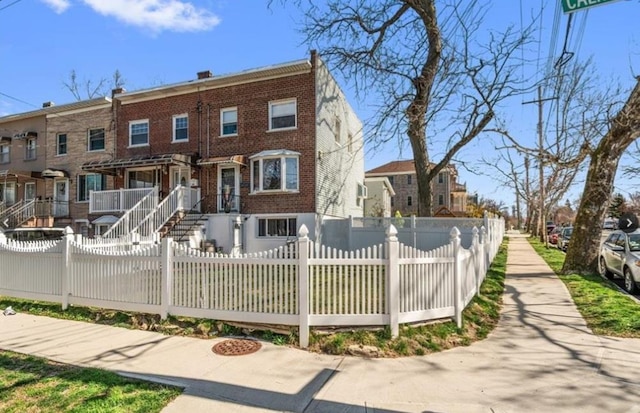 view of property with brick siding, a residential view, and a fenced front yard