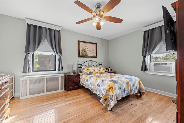 bedroom featuring hardwood / wood-style flooring, cooling unit, radiator, baseboards, and ceiling fan