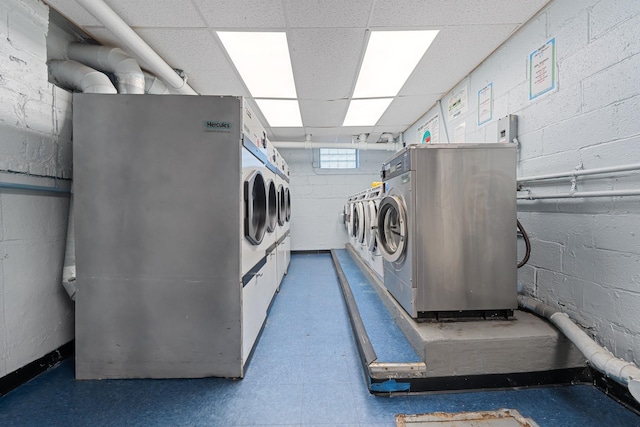 common laundry area with concrete block wall and washer and clothes dryer