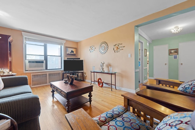 living area featuring radiator, wood finished floors, baseboards, and cooling unit