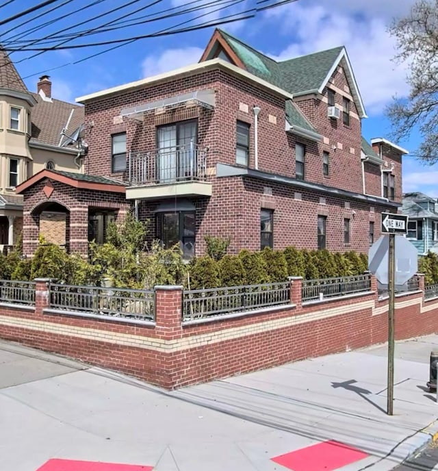 exterior space featuring a fenced front yard, brick siding, and a balcony