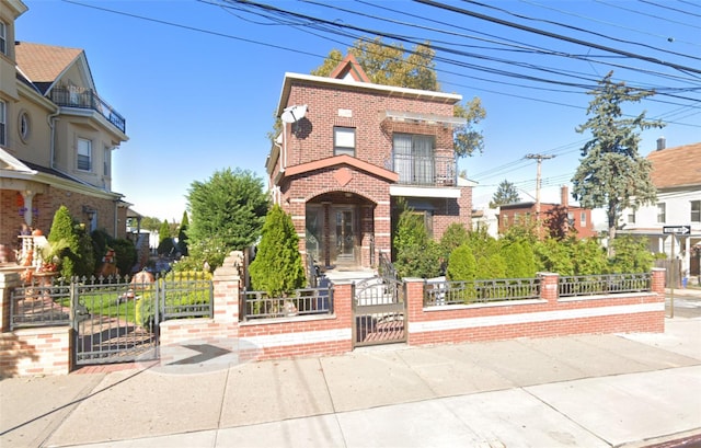 view of front of house with brick siding, a balcony, a fenced front yard, and a gate