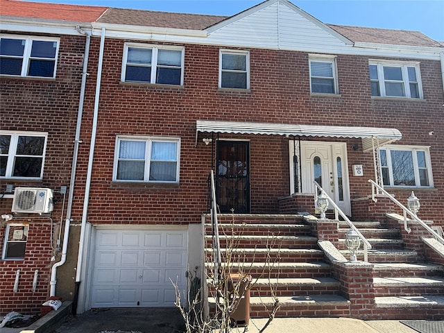 multi unit property featuring brick siding, an attached garage, and a shingled roof