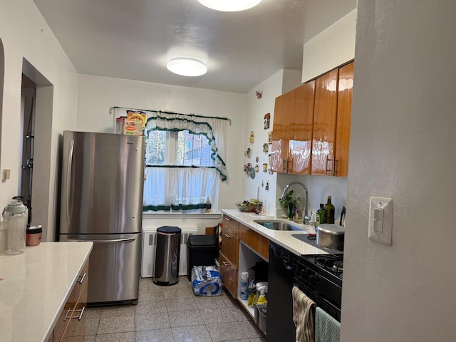 kitchen with granite finish floor, light countertops, brown cabinetry, black appliances, and a sink