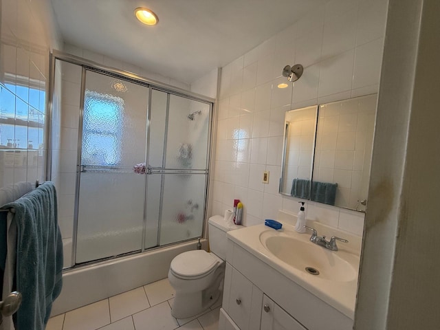 full bath featuring tile walls, toilet, tile patterned floors, vanity, and enclosed tub / shower combo