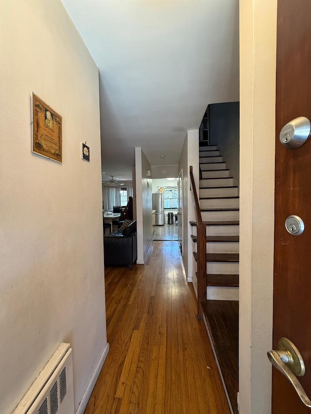 hallway with baseboards, radiator, wood finished floors, and stairs