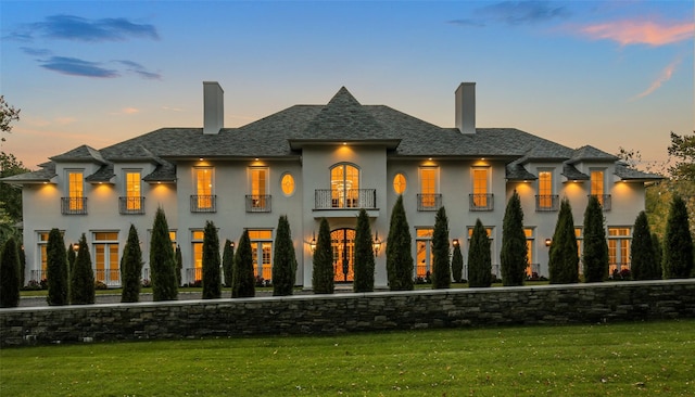 view of front of home featuring a front lawn, a balcony, and a chimney