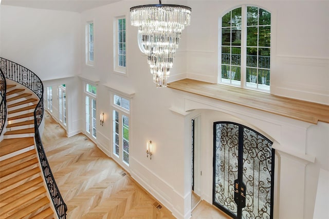 foyer entrance featuring stairs, plenty of natural light, french doors, and a chandelier