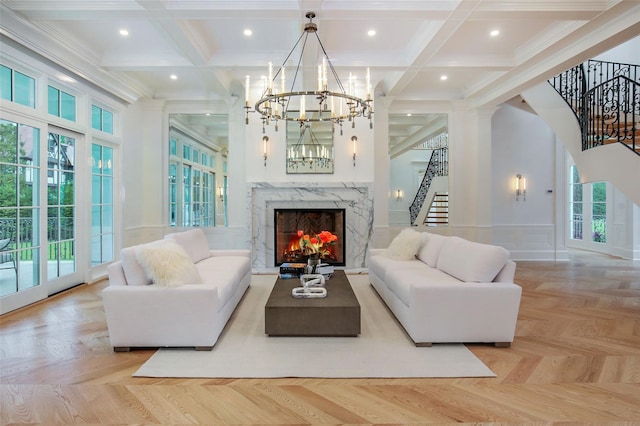 living area featuring coffered ceiling, a premium fireplace, beam ceiling, an inviting chandelier, and stairs