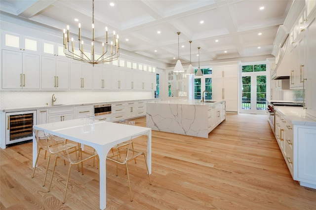 kitchen featuring light wood-style floors, wine cooler, a spacious island, and tasteful backsplash