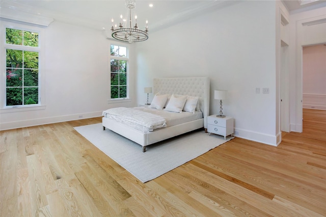 bedroom with a notable chandelier, baseboards, and light wood-style floors